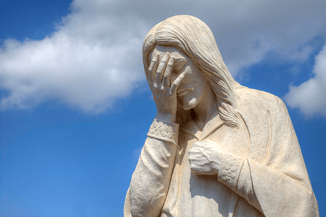 Statue of Jesus with hand in his face showing sadness