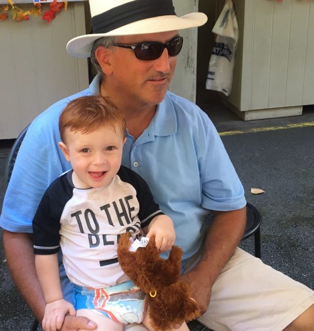 Grandfather with two year old red headed grand baby sitting on his lap