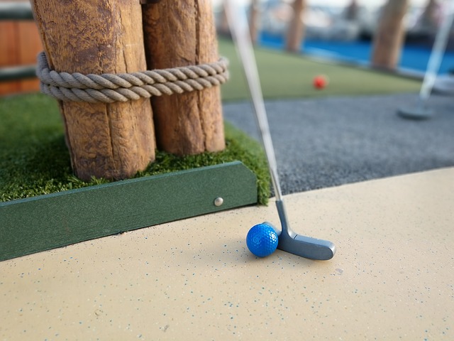 Blue golf ball next to putter at a miniature golf course