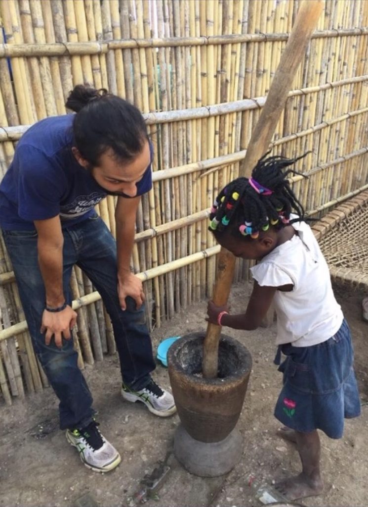 Abel with young girl in Mozambique preparing food.