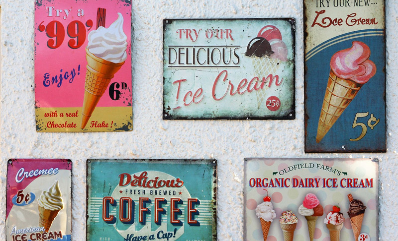 Photo of old fashioned tin ice cream signs hanging on wall
