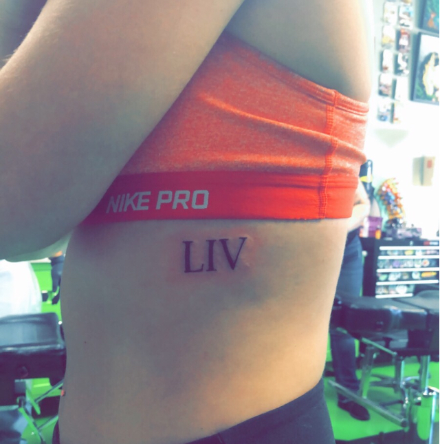 Young woman's torso with number 54 tattooed in Roman numerals on her side