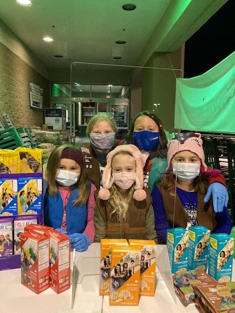 5 girl scouts selling cookies