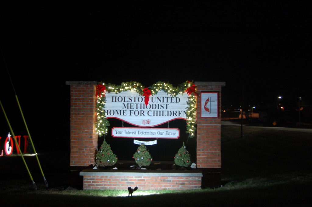 shows the Holston Home gate decked out with Christmas lights