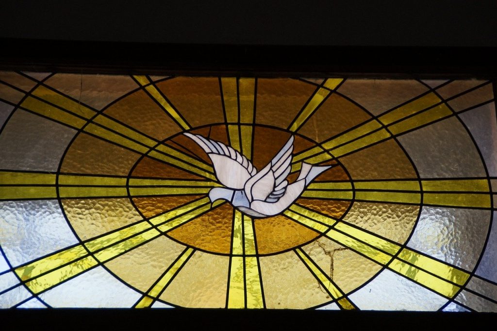 Stained glass window of a dove in a yellow ray of light