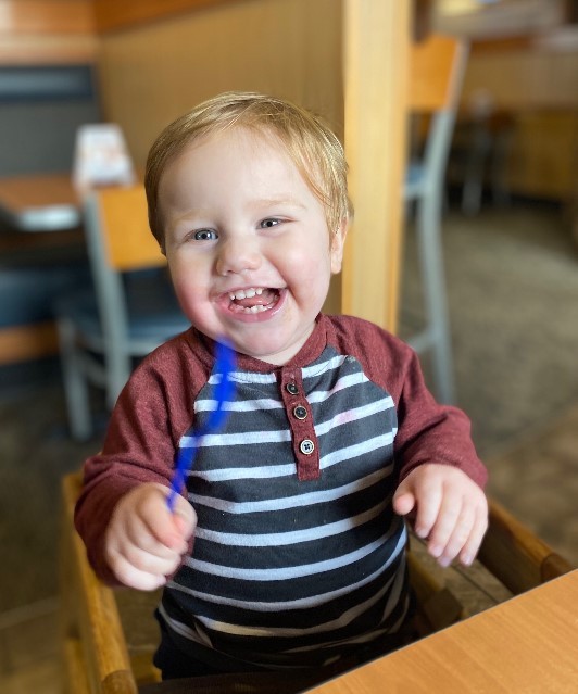 a smiling happy boy wearing a blue stripped shirt right after receiving his treatment